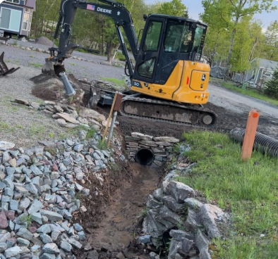 Excavator installing culvert pipe